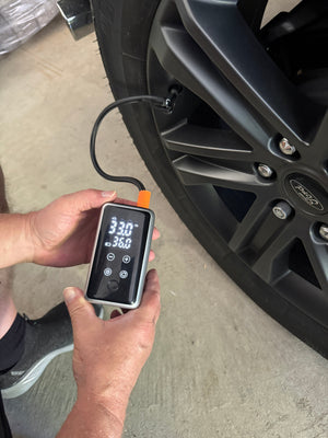 The JumpAir Pro filling a tire: the screen shows 33.0 psi on its way to the 35.0 target